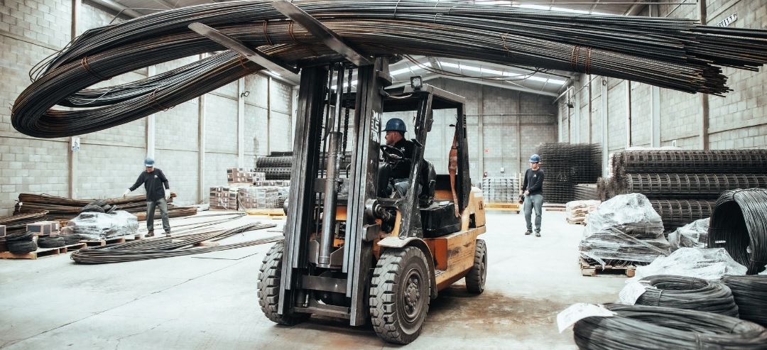 Trabajador manejando equipo industrial o de construcción dentro de una bodega o nave industrial