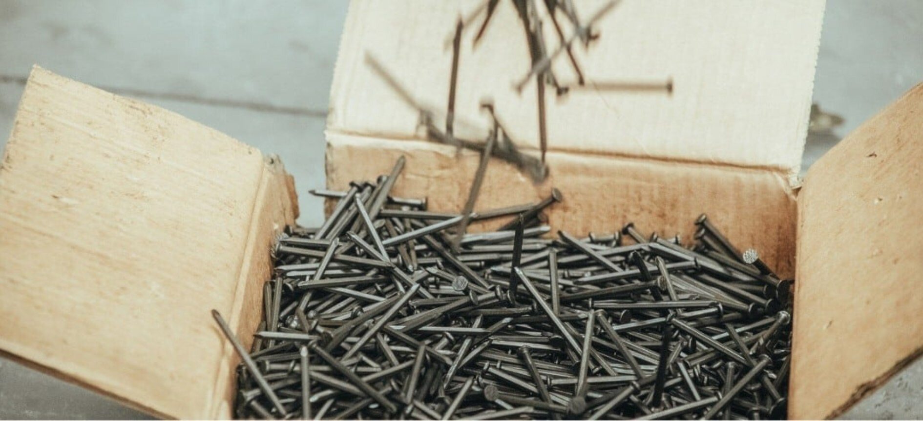Diferentes tipos de clavos de Mexlam cayendo en una caja de cartón